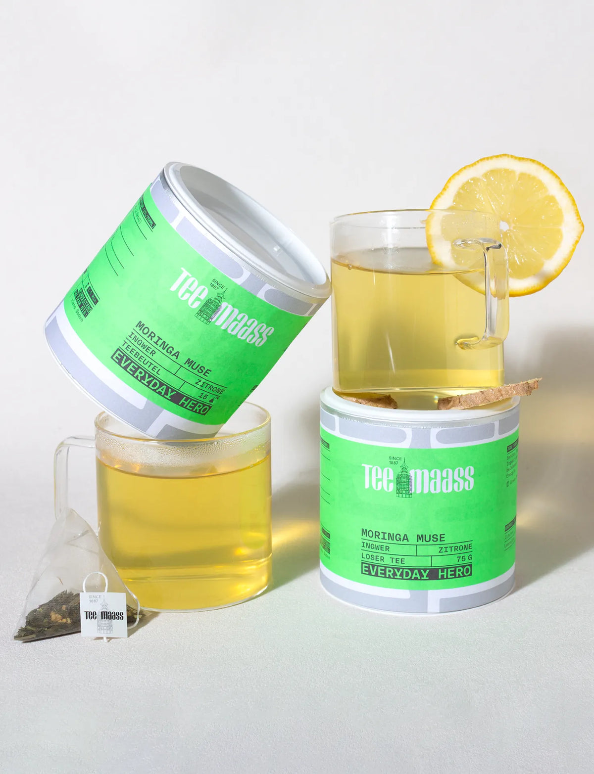 Tee Maass Moringa Muse loser Grüntee in Dose mit frisch aufgebrühtem Tee und Zitrone und Pyramiden-Teebeutel